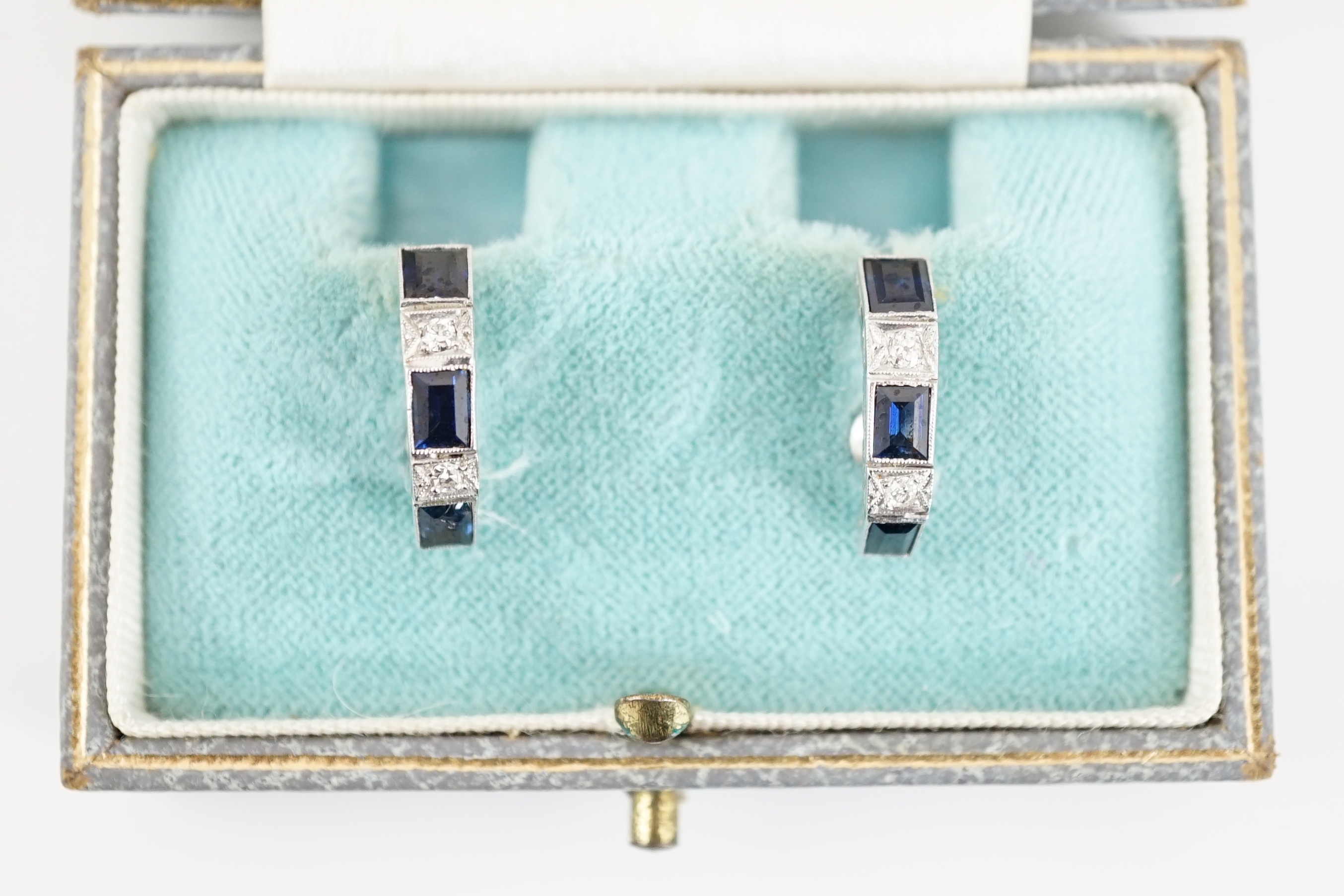 A pair of 9ct white gold, three stone sapphire and two stone diamond set half hoop ear clips, 16mm, gross weight 4.1 grams.